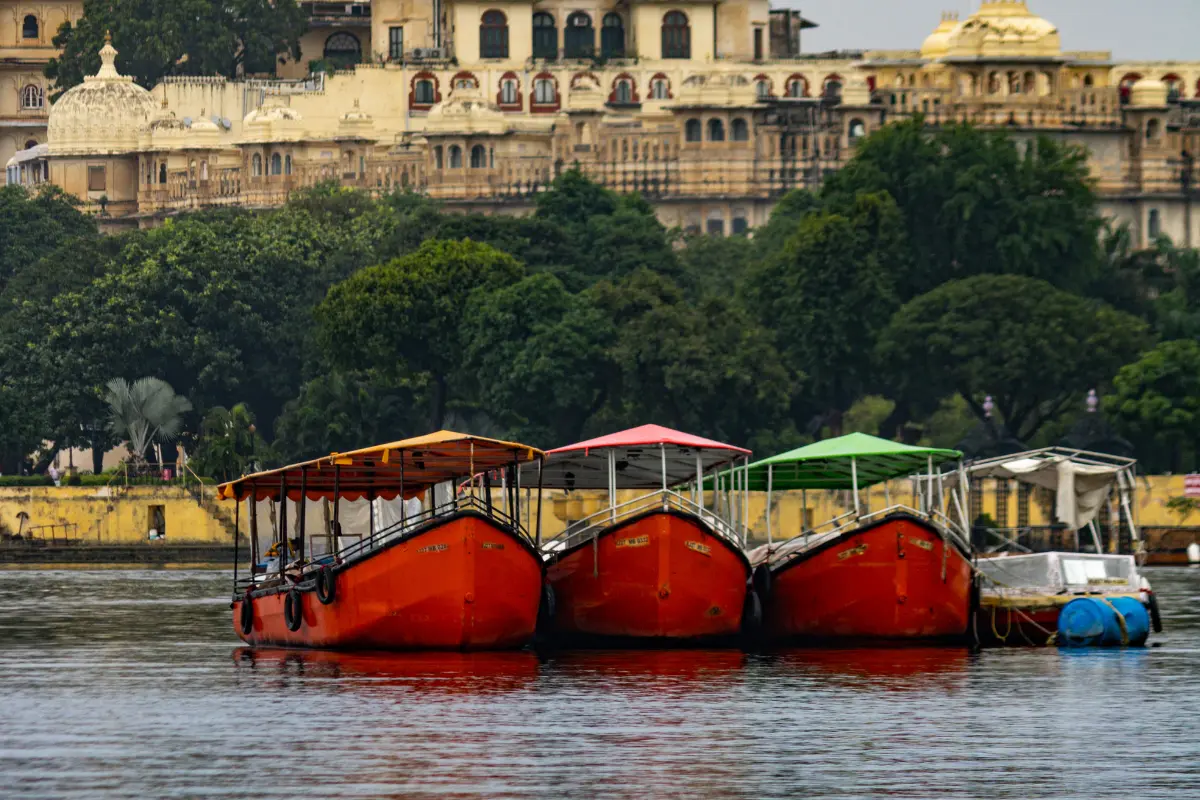 A beautiful lake in Udaipur with boats floating on the water and a palace in the background.